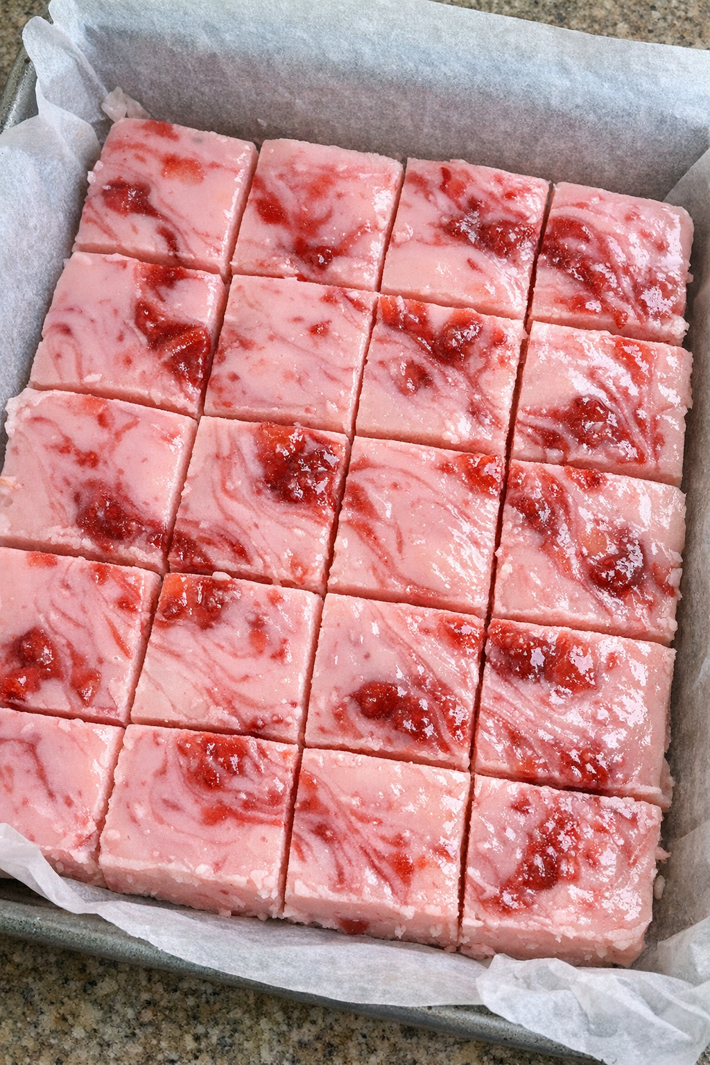 Slow cooker strawberry milk fudge in a parchment-lined baking sheet