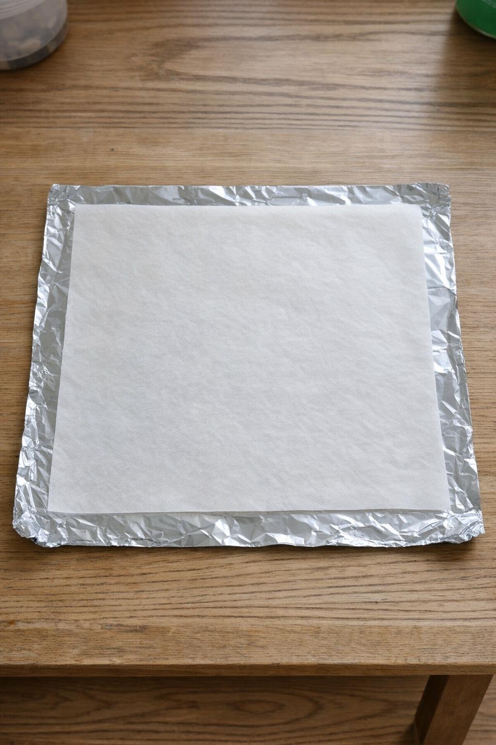 Foil and parchment layered on a table to form the tile base