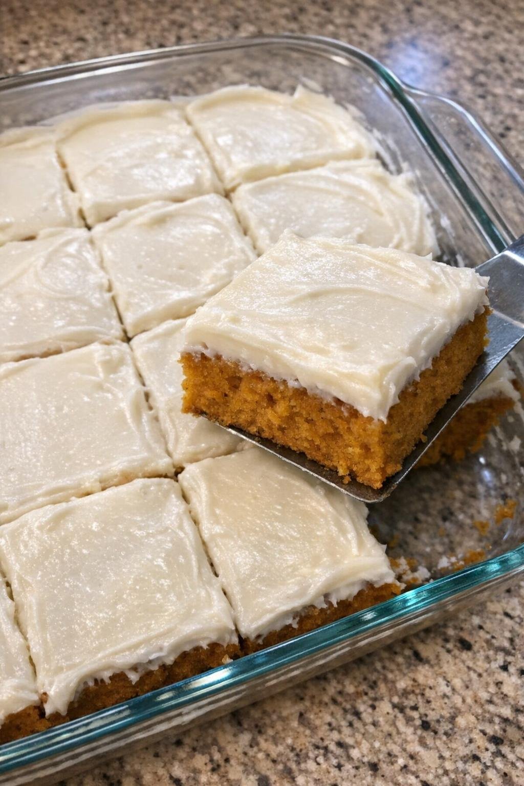 Pumpkin bars with cream cheese frosting cut into squares in a glass casserole dish