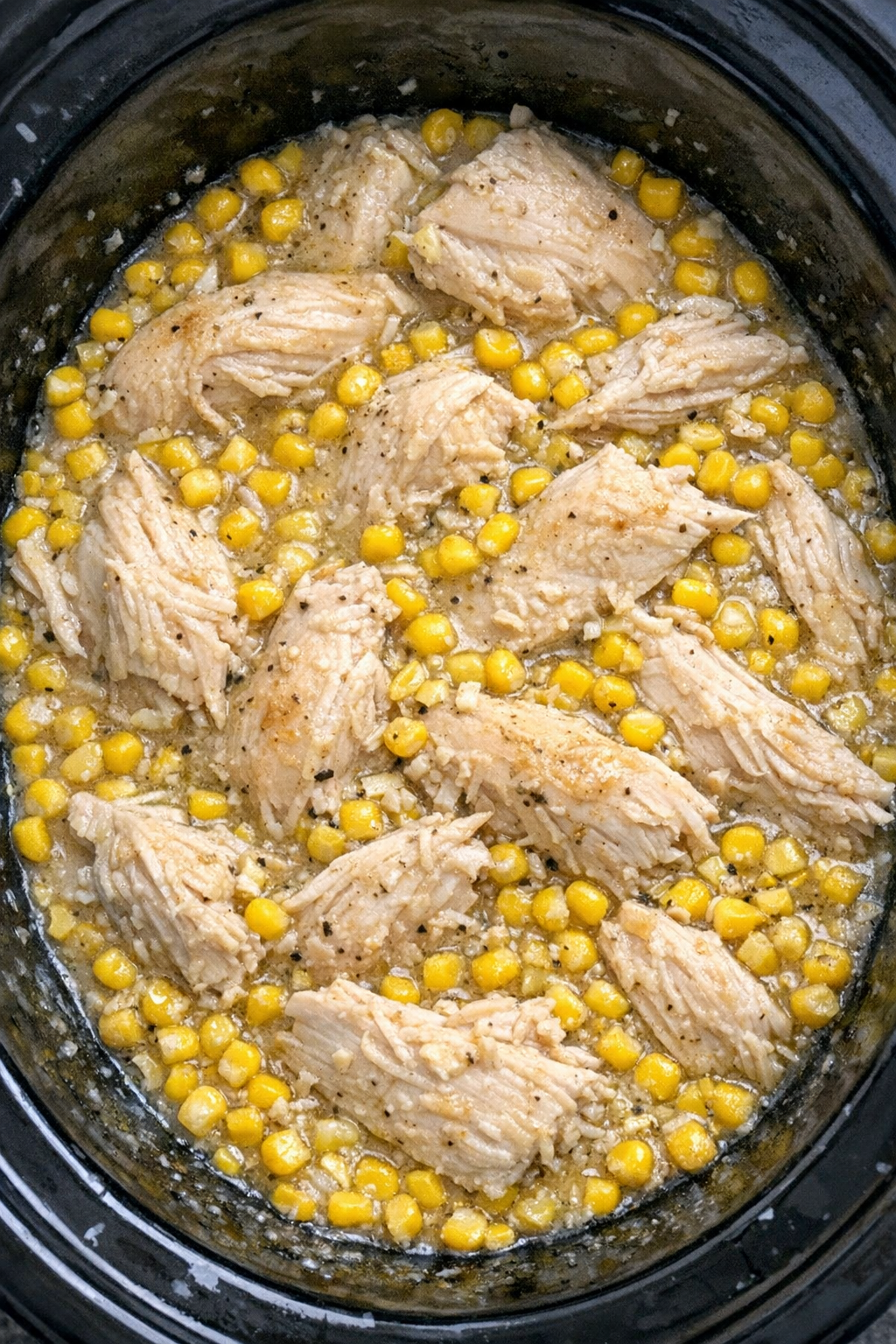 Slow cooker chicken and sweet corn in a black slow cooker
