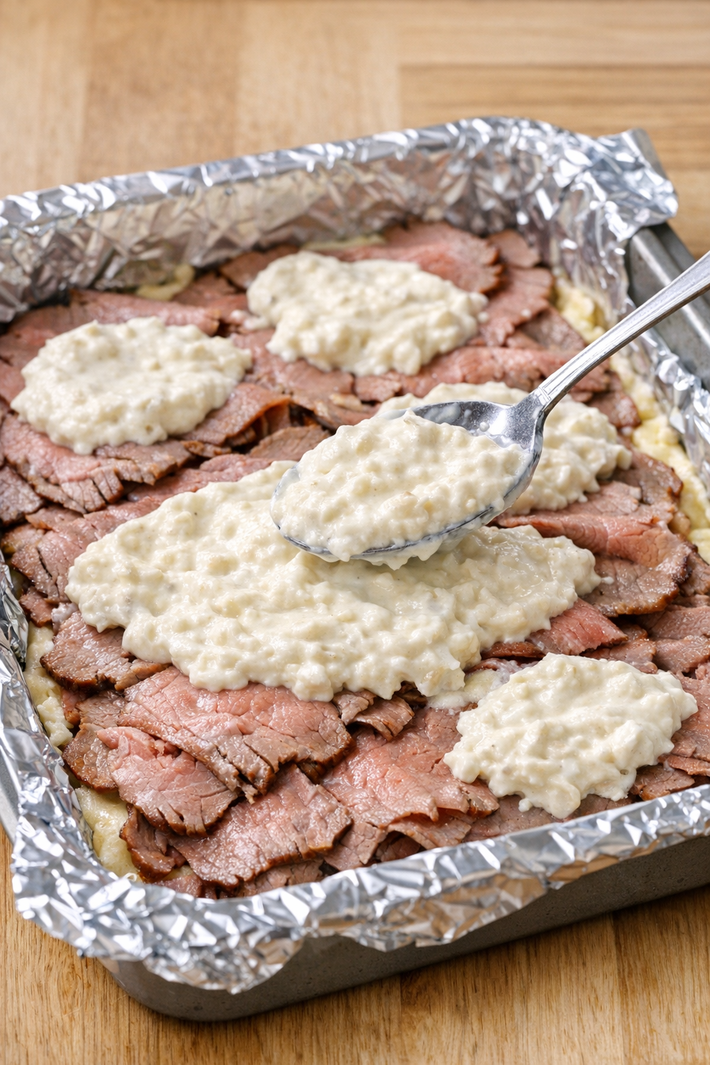 Roast beef layered in pan with creamy topping