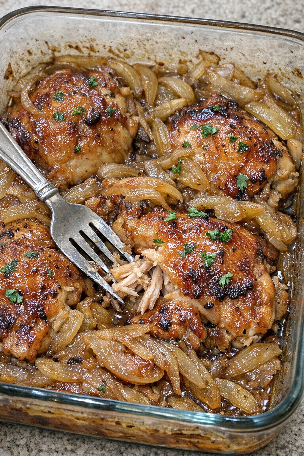 Glazed chicken thighs with caramelized onions in a baking dish