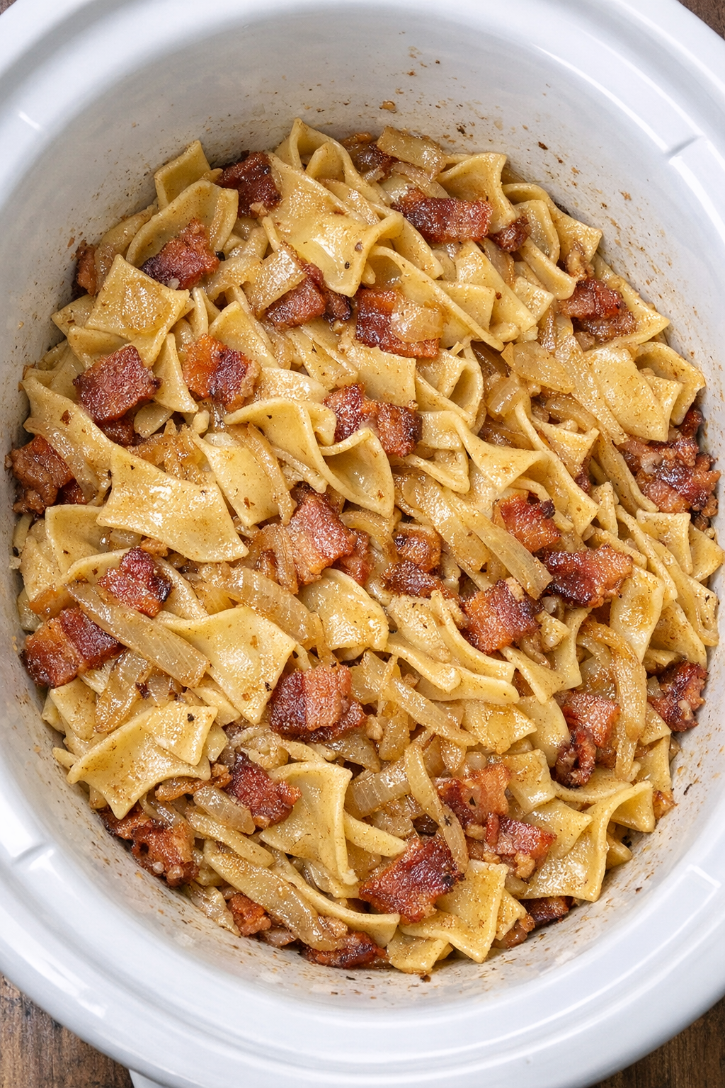 Slow cooker Amish bacon onion noodles in a white slow cooker