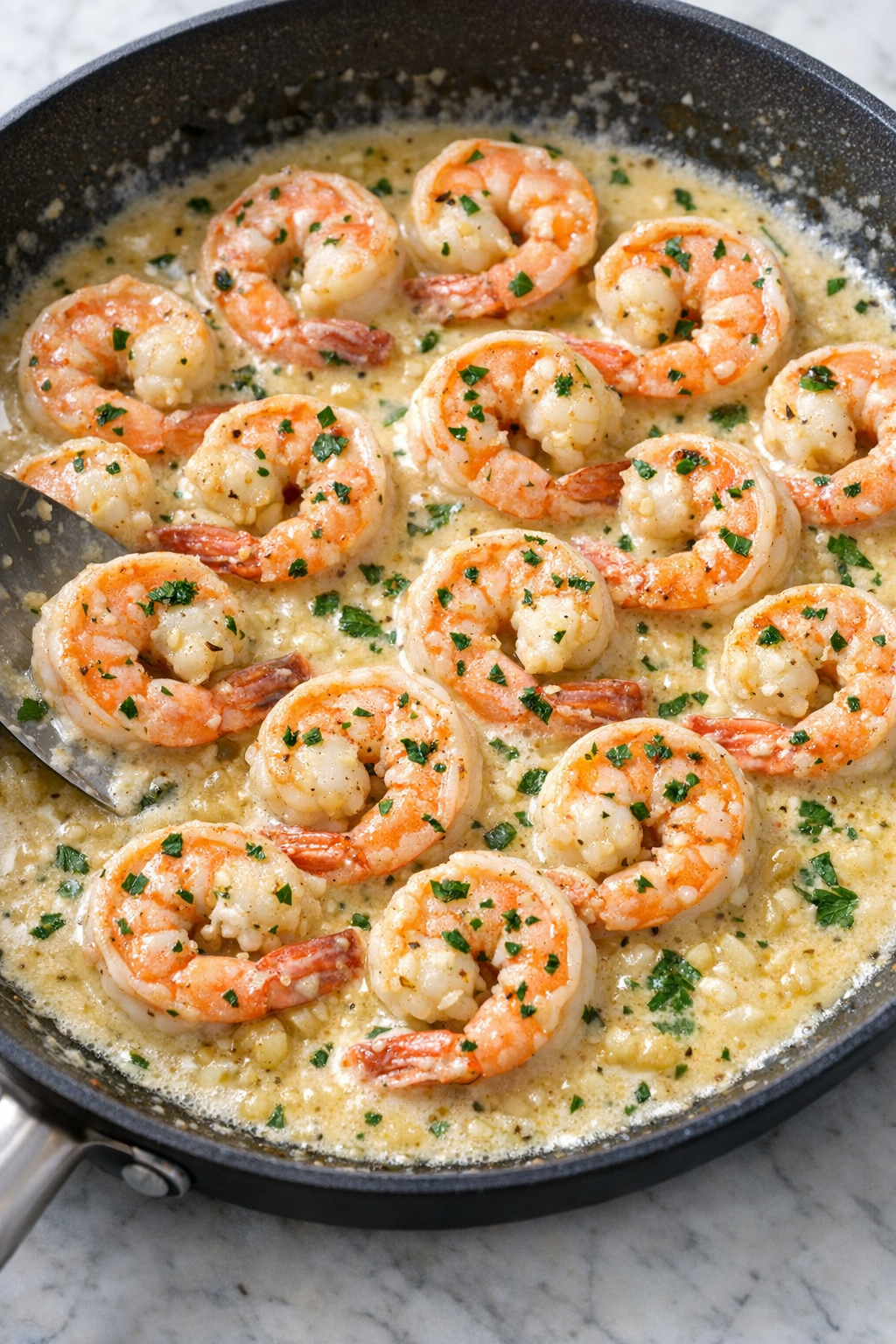 Cream sauce simmering with shrimp in skillet