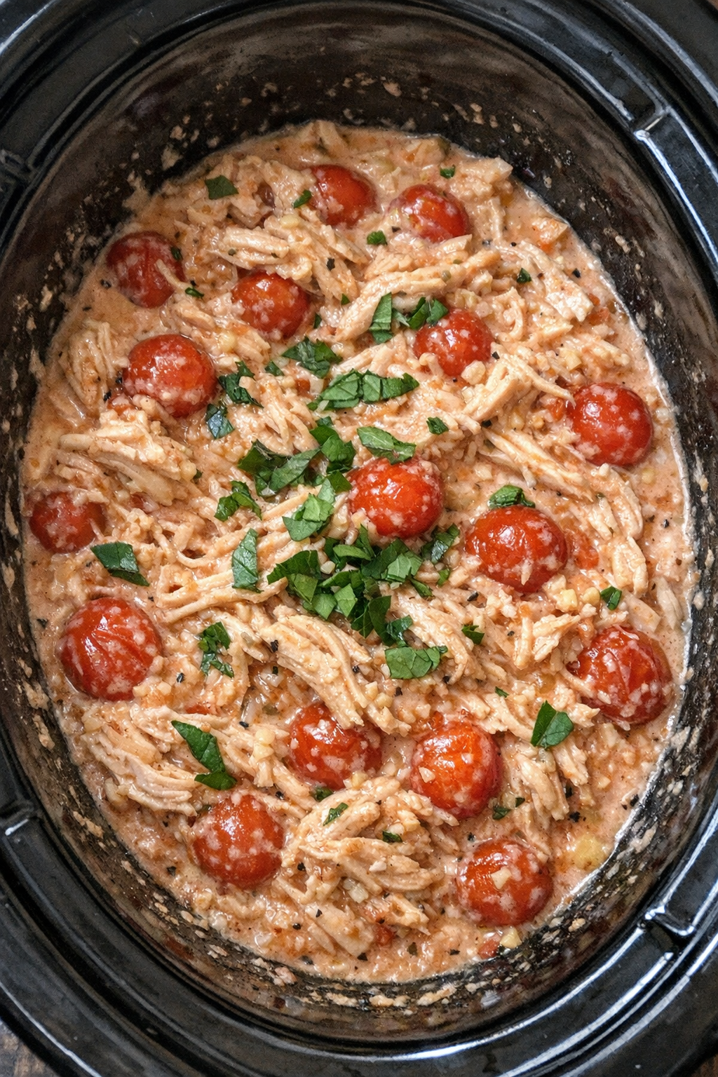 Slow cooker creamy cherry tomato chicken in a black slow cooker
