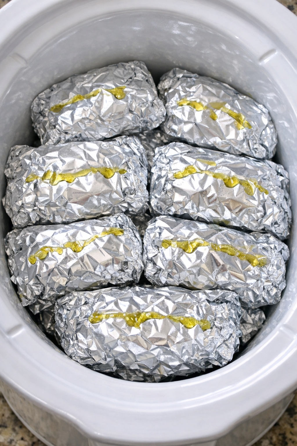 Slow cooker foil pasta packets in a white slow cooker