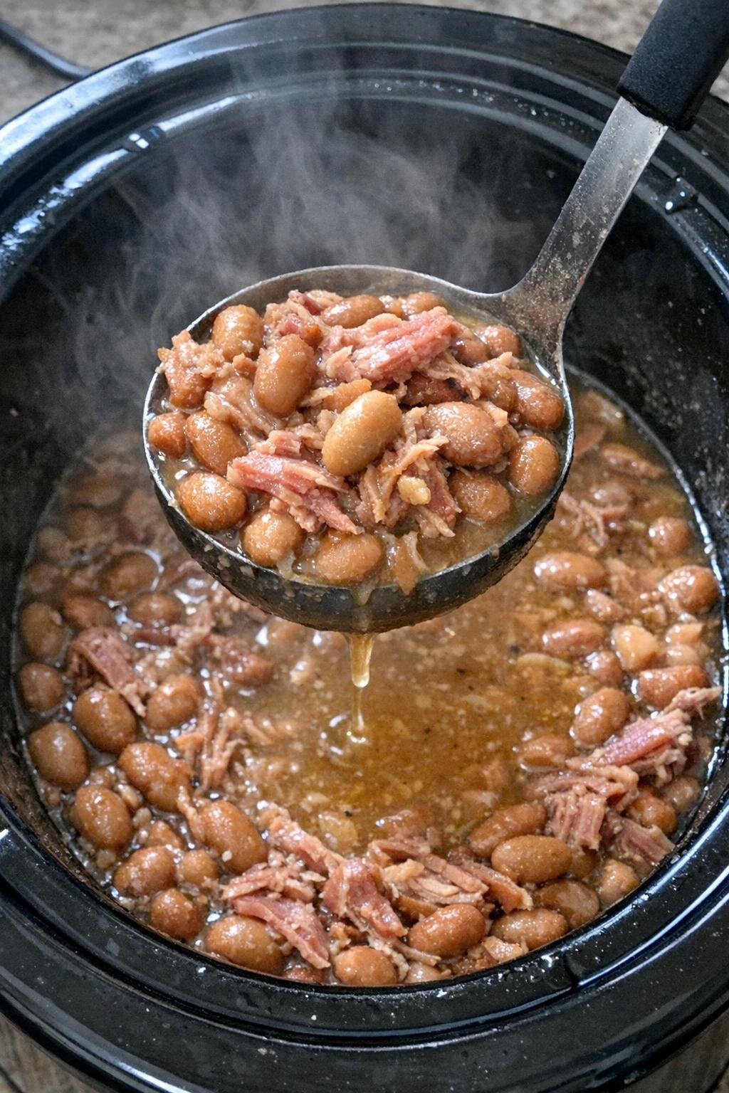 Slow cooker pinto beans with ham in a black insert