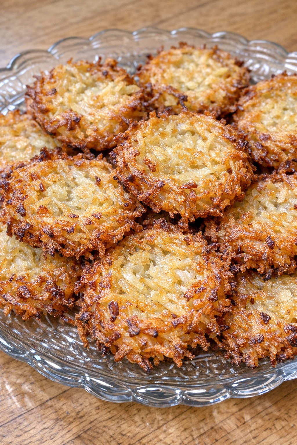 Golden crispy shredded potato rounds on a glass serving plate