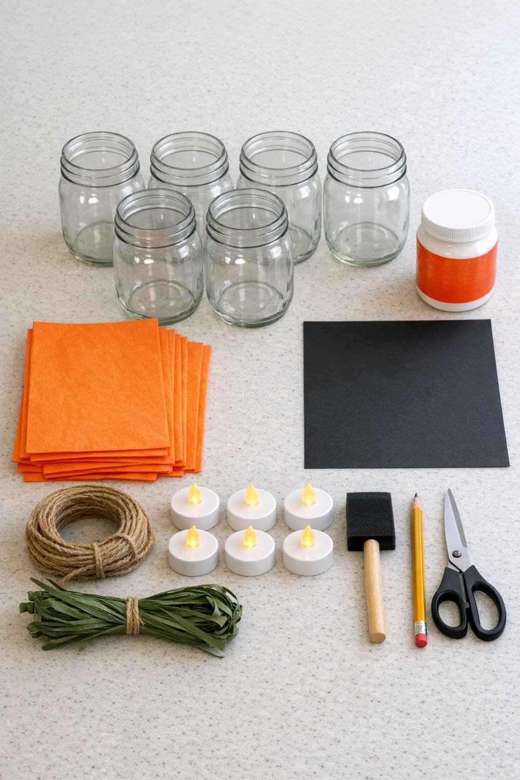 Materials for making tissue paper Halloween jars laid out on a counter