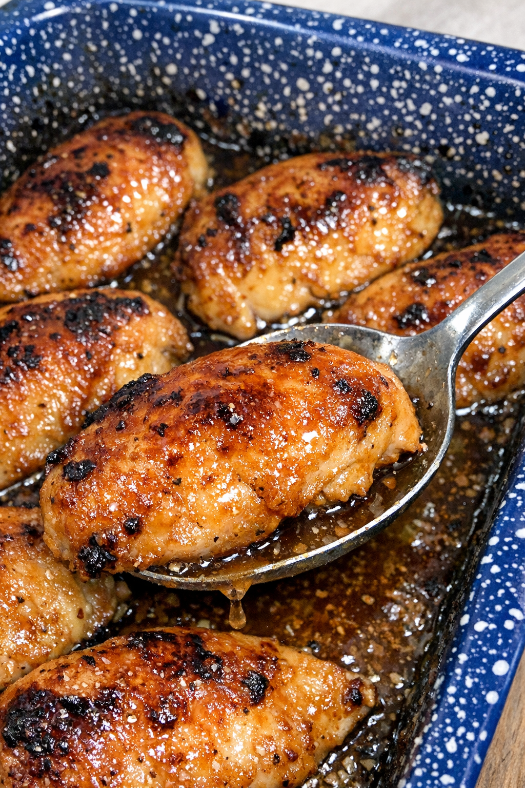 Glazed chicken breasts in a blue speckled enamel baking pan