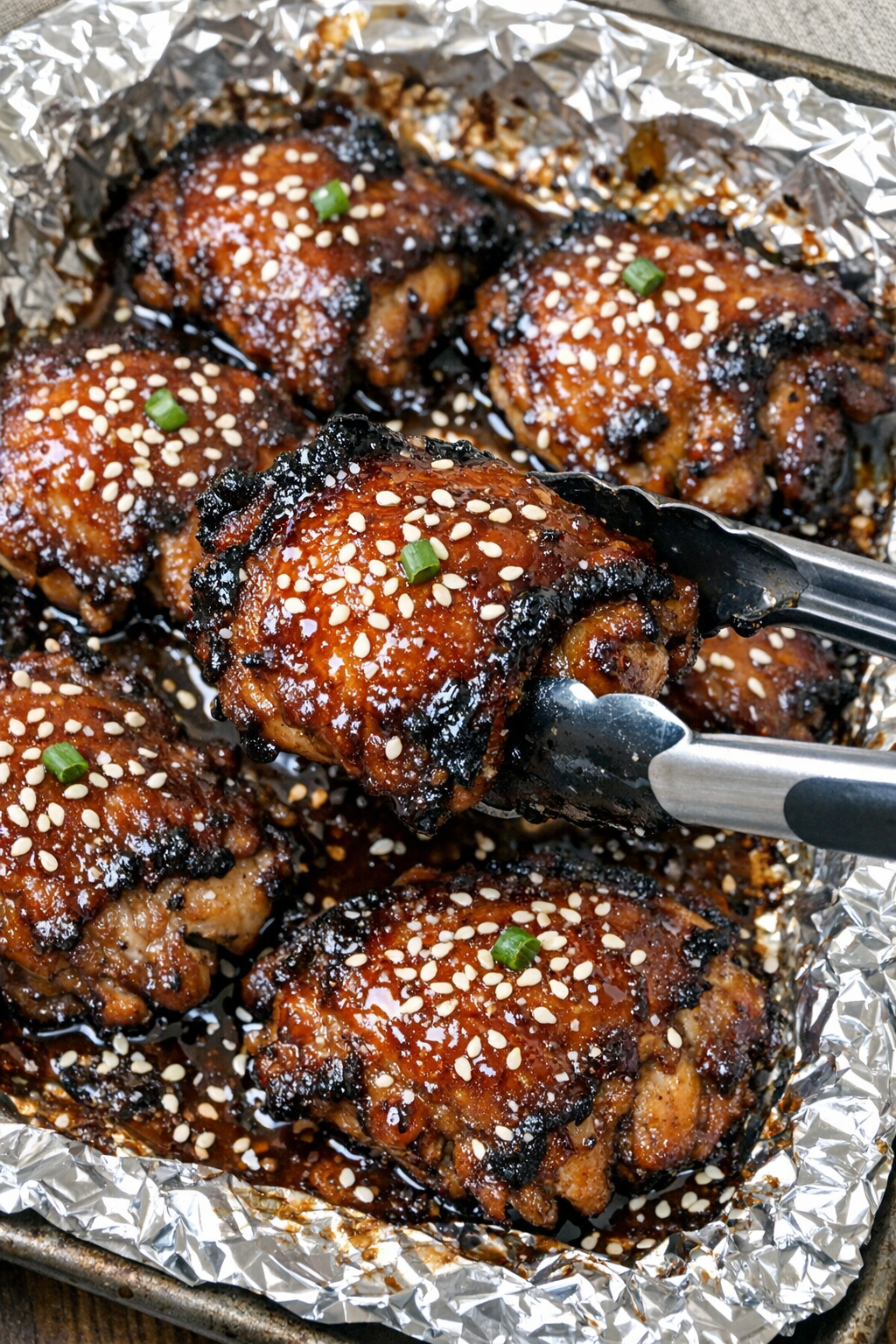 Glossy caramelized chicken thighs with teriyaki glaze in a foil-lined baking sheet