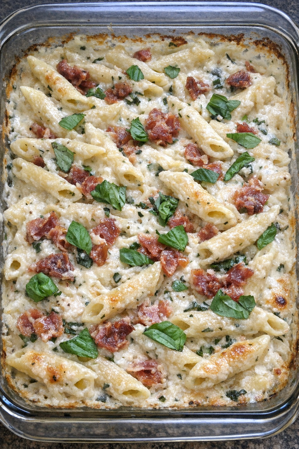 Creamy basil prosciutto penne in a glass baking dish