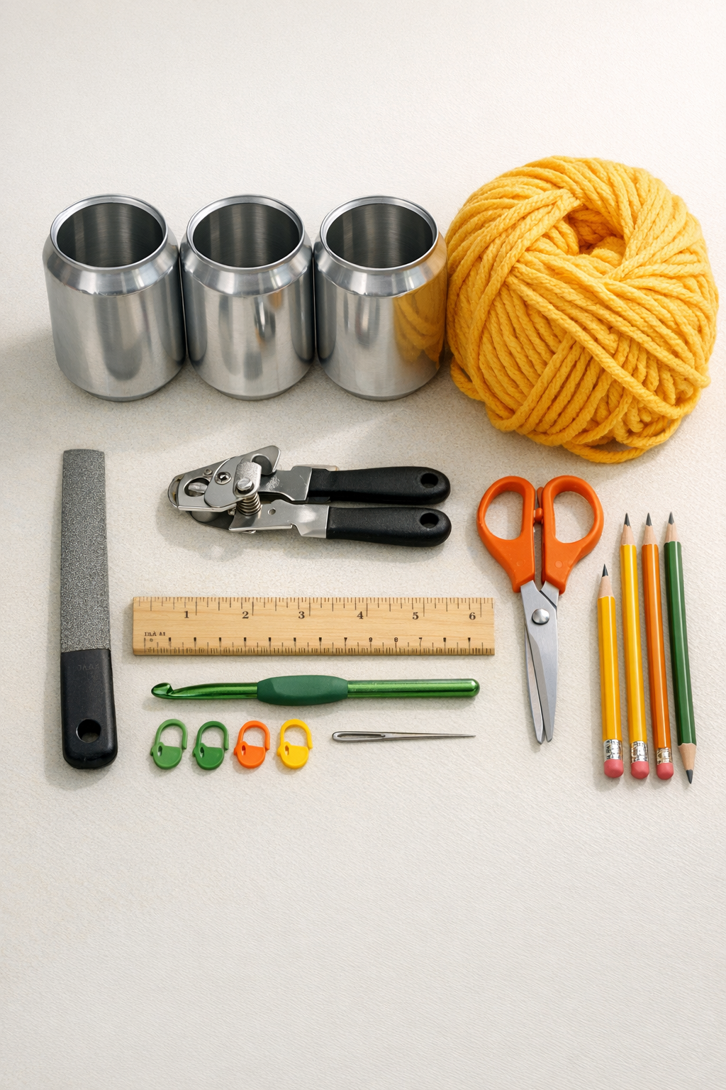Materials for crocheted soda can pencil cups laid out on a table