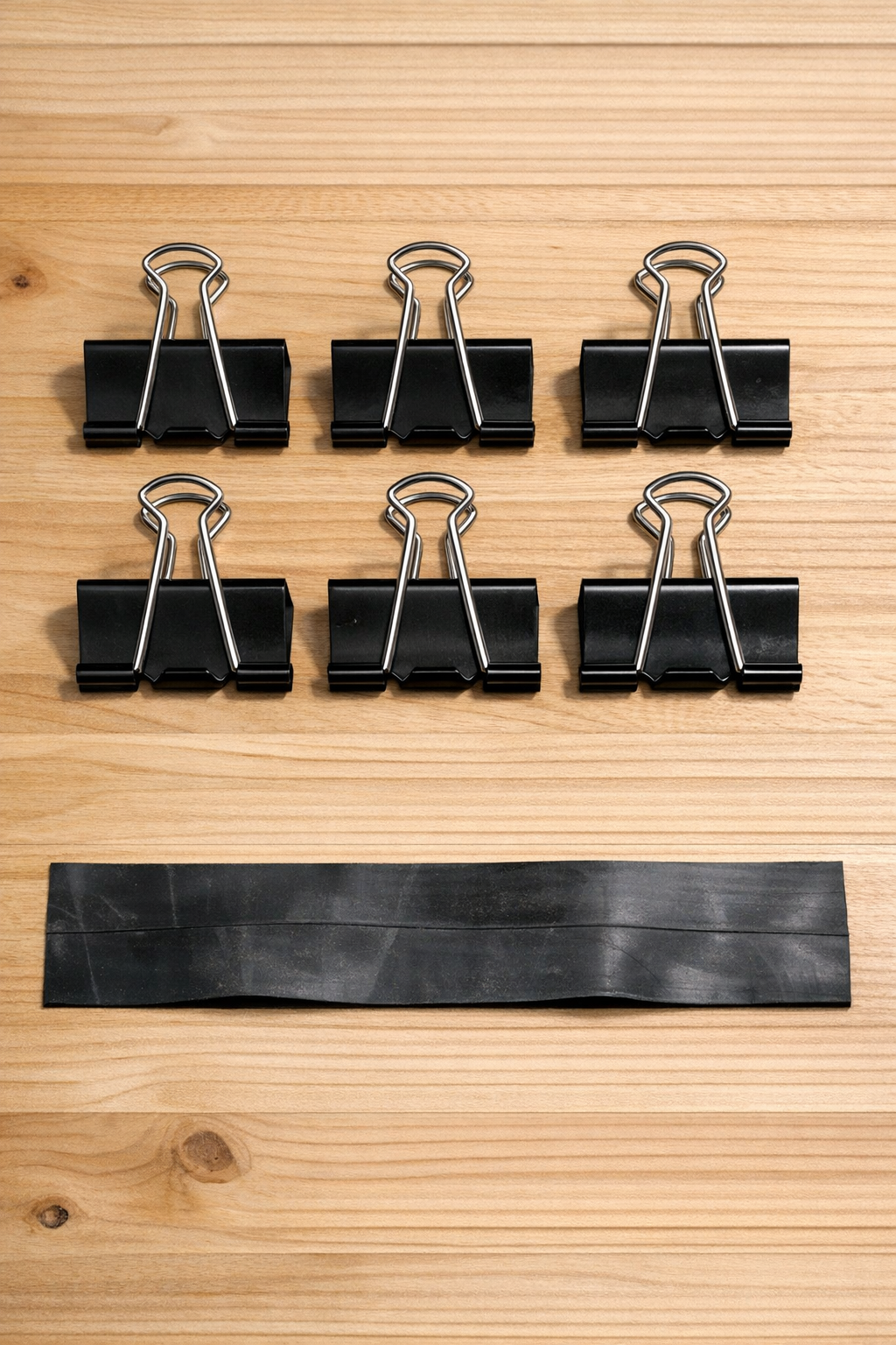 Jumbo binder clips and rubber strip laid out for making cable clamps