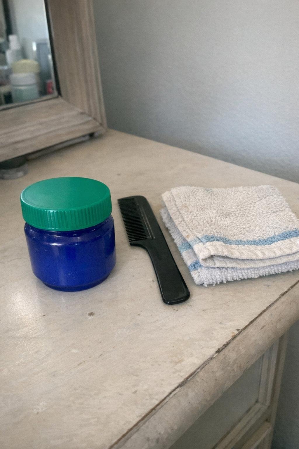 VapoRub jar with a comb and folded washcloth on a vanity