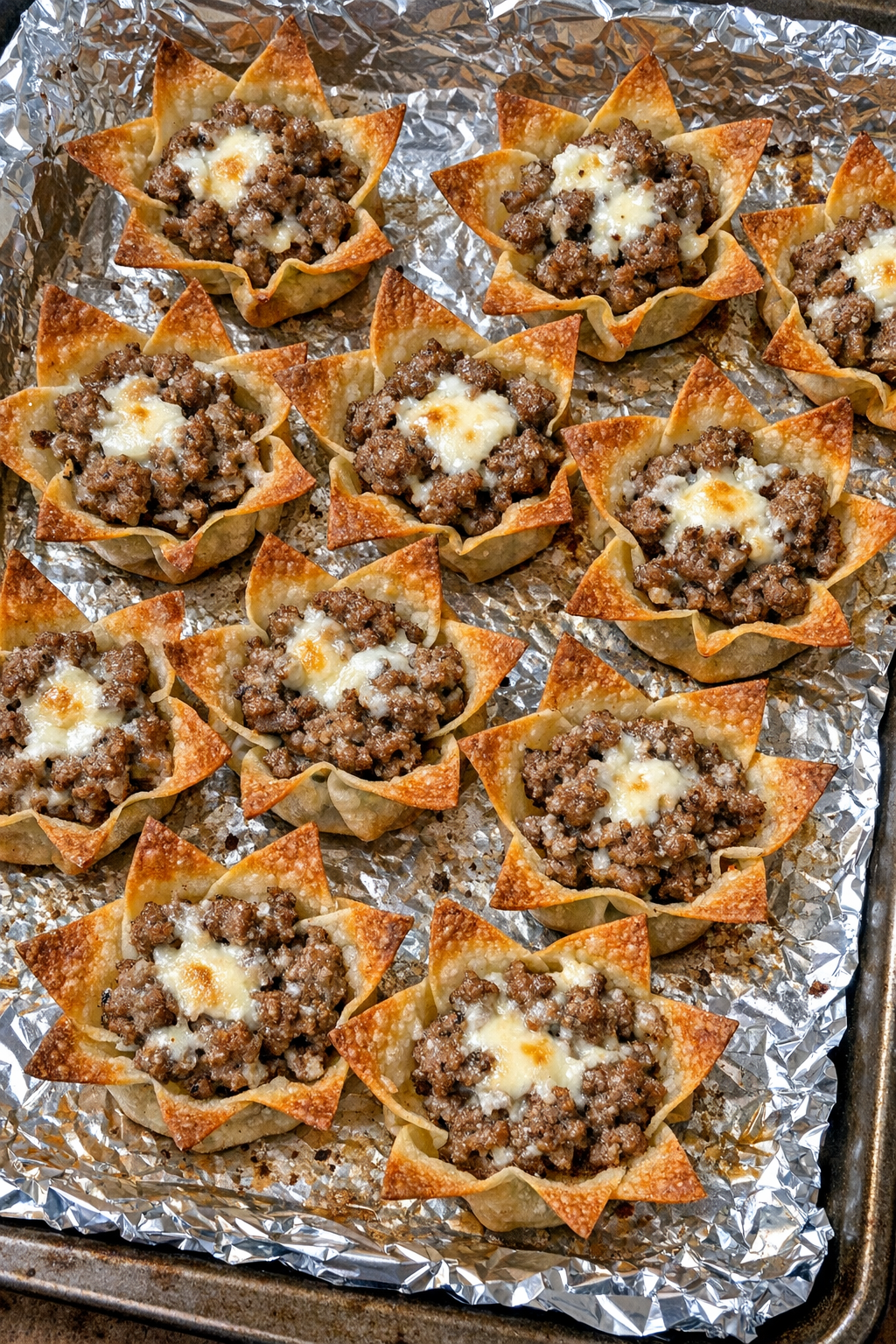 Oven baked beef wonton stars on a foil-lined baking sheet