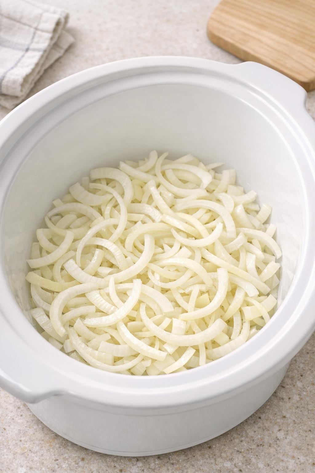 Sliced onions spread in the bottom of a slow cooker