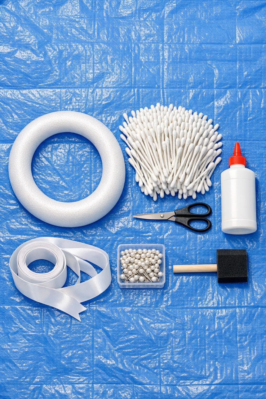 Cotton swabs, foam wreath form, scissors, glue, and ribbon laid out for the project