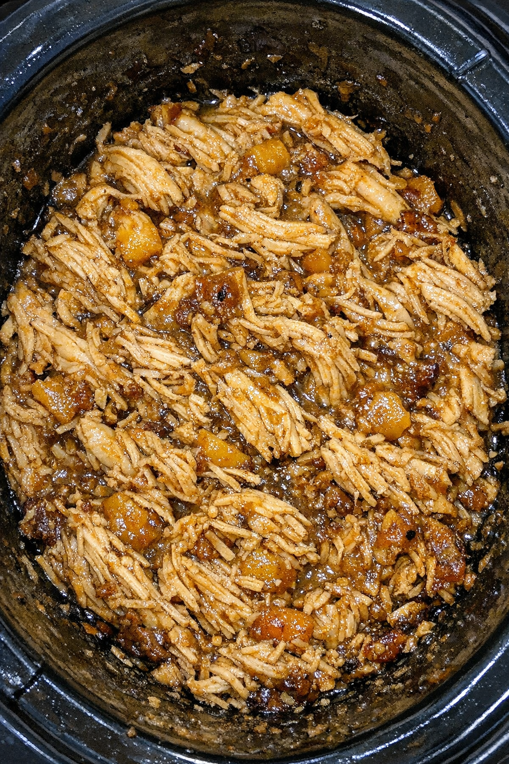 Slow cooker peach jam chicken in a black slow cooker