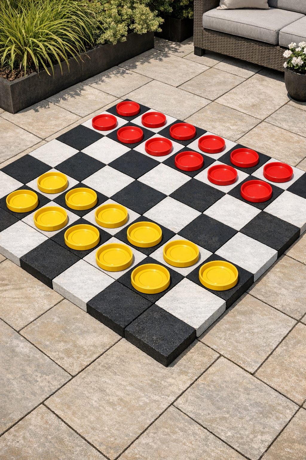 Finished oversized patio checkerboard made from painted concrete pavers and plastic plant saucer pieces