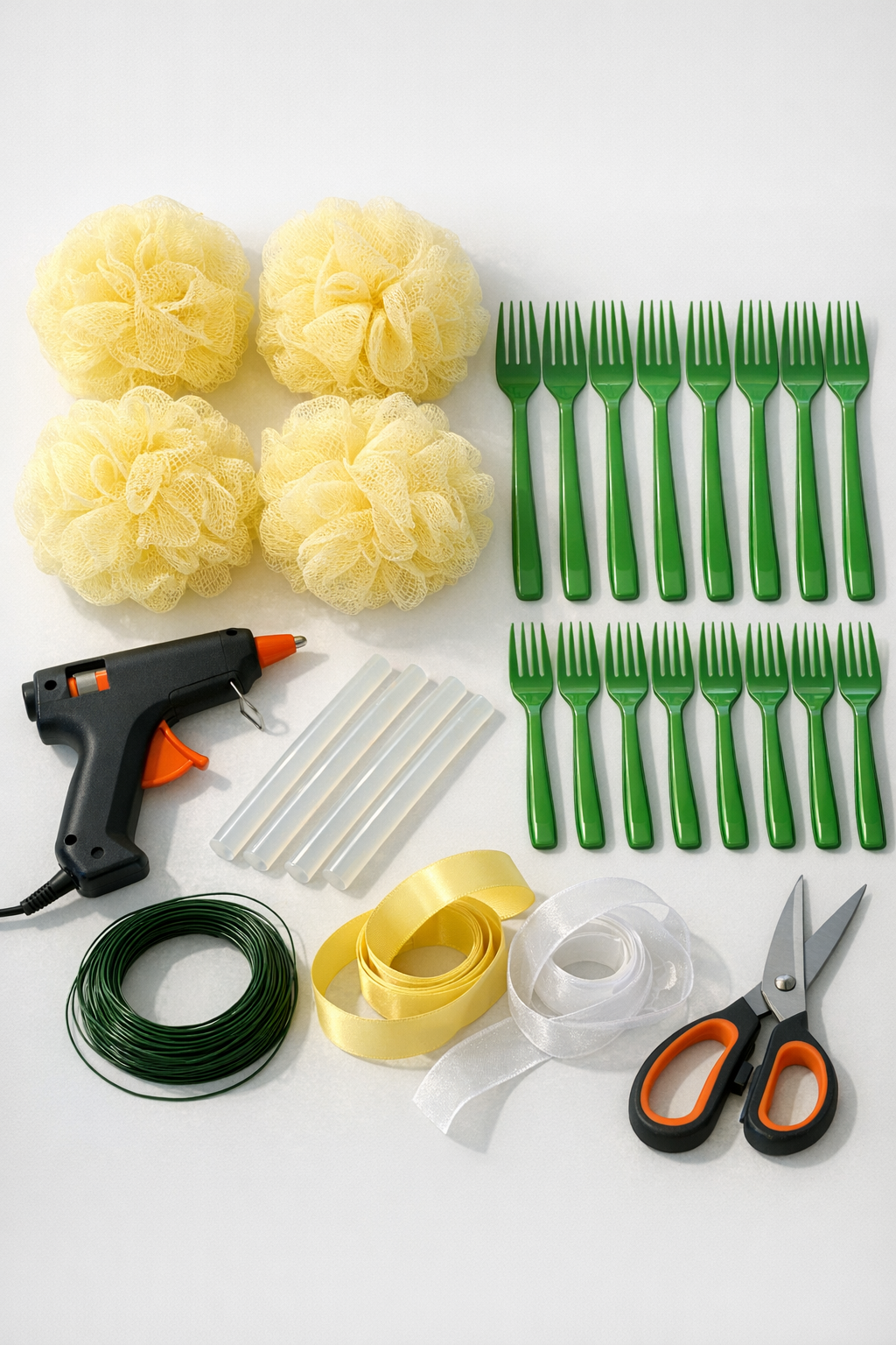 Yellow bath loofahs, green plastic forks, glue, and hanging supplies laid out for the project