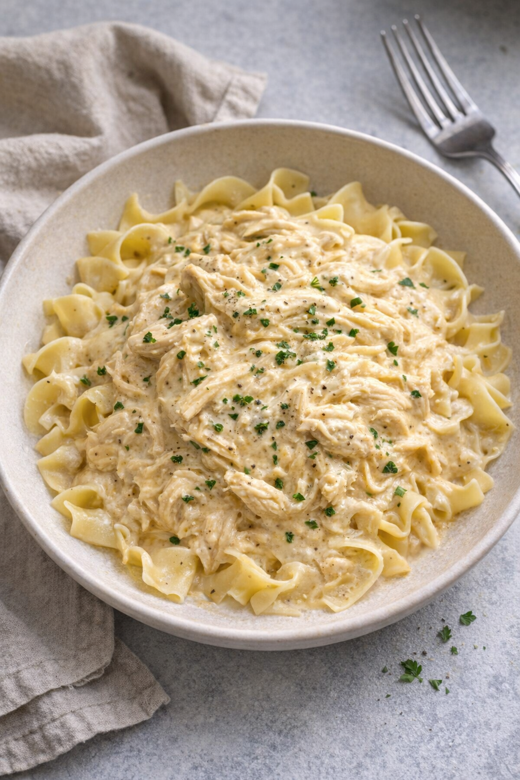 Slow cooker cream cheese chicken served over egg noodles
