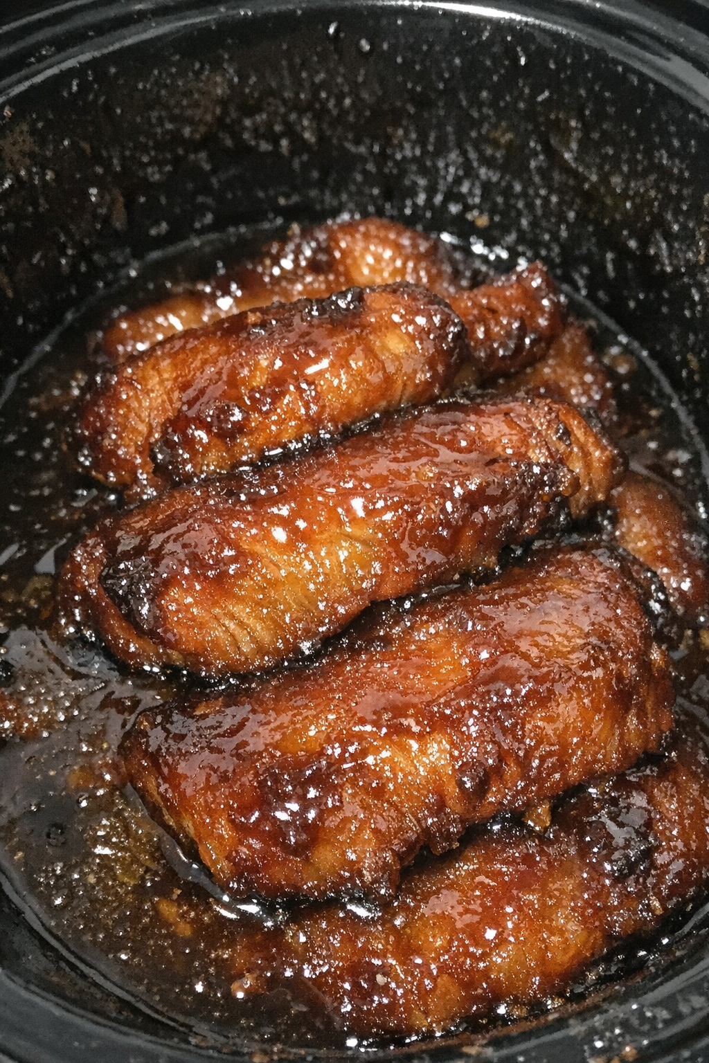 Glistening glazed protein slices in a slow cooker