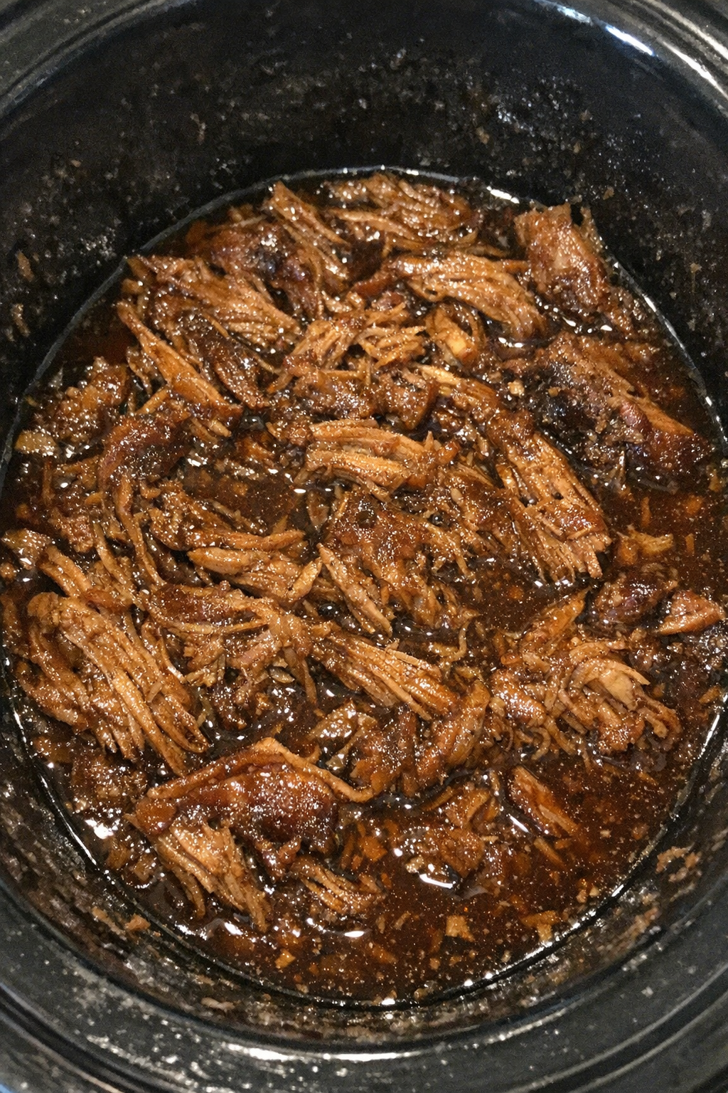 Slow cooker shredded meat in dark amber sauce