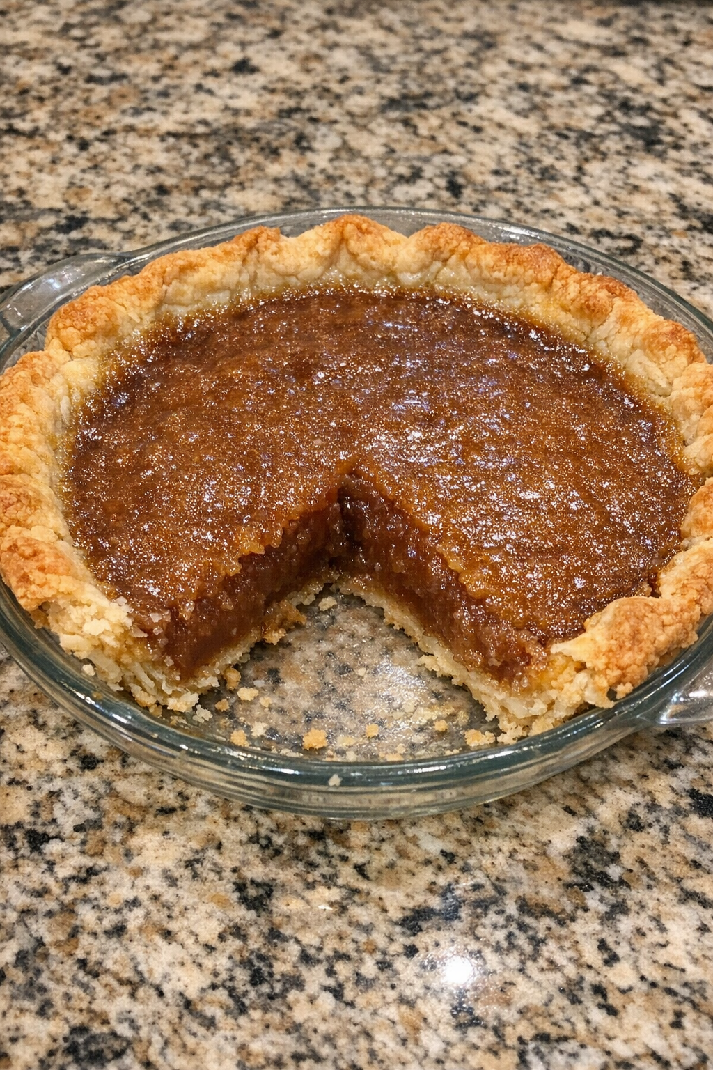 Brown sugar pie in a glass pie plate with glossy filling and flaky crust