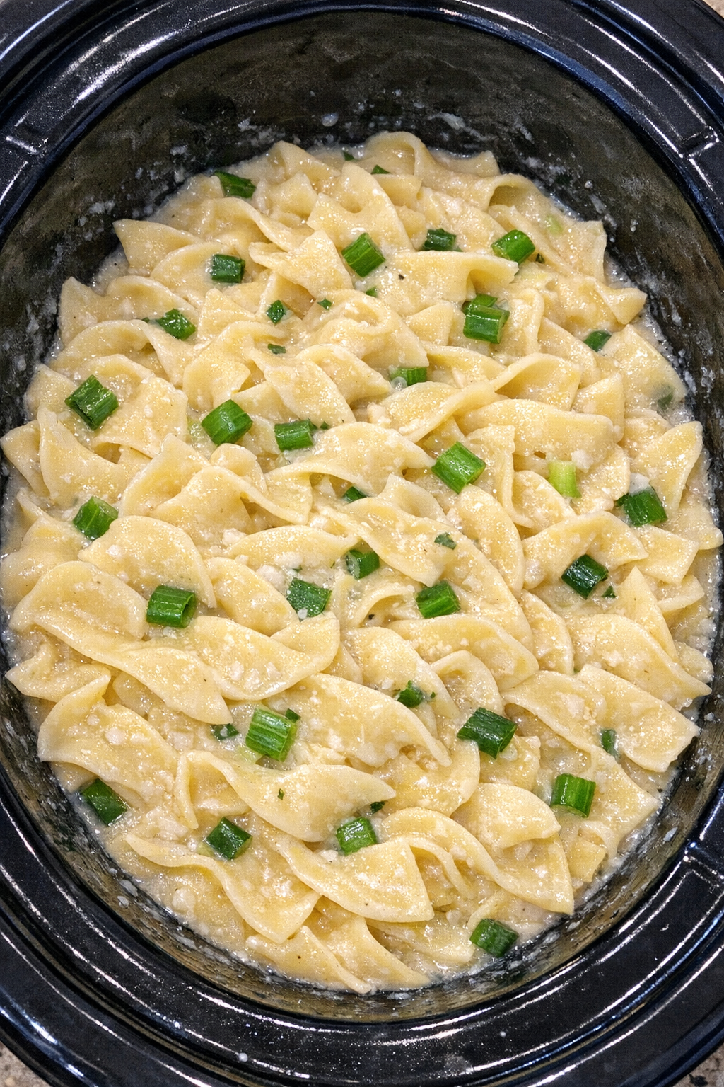Slow cooker Amish green onion cream noodles in a black slow cooker
