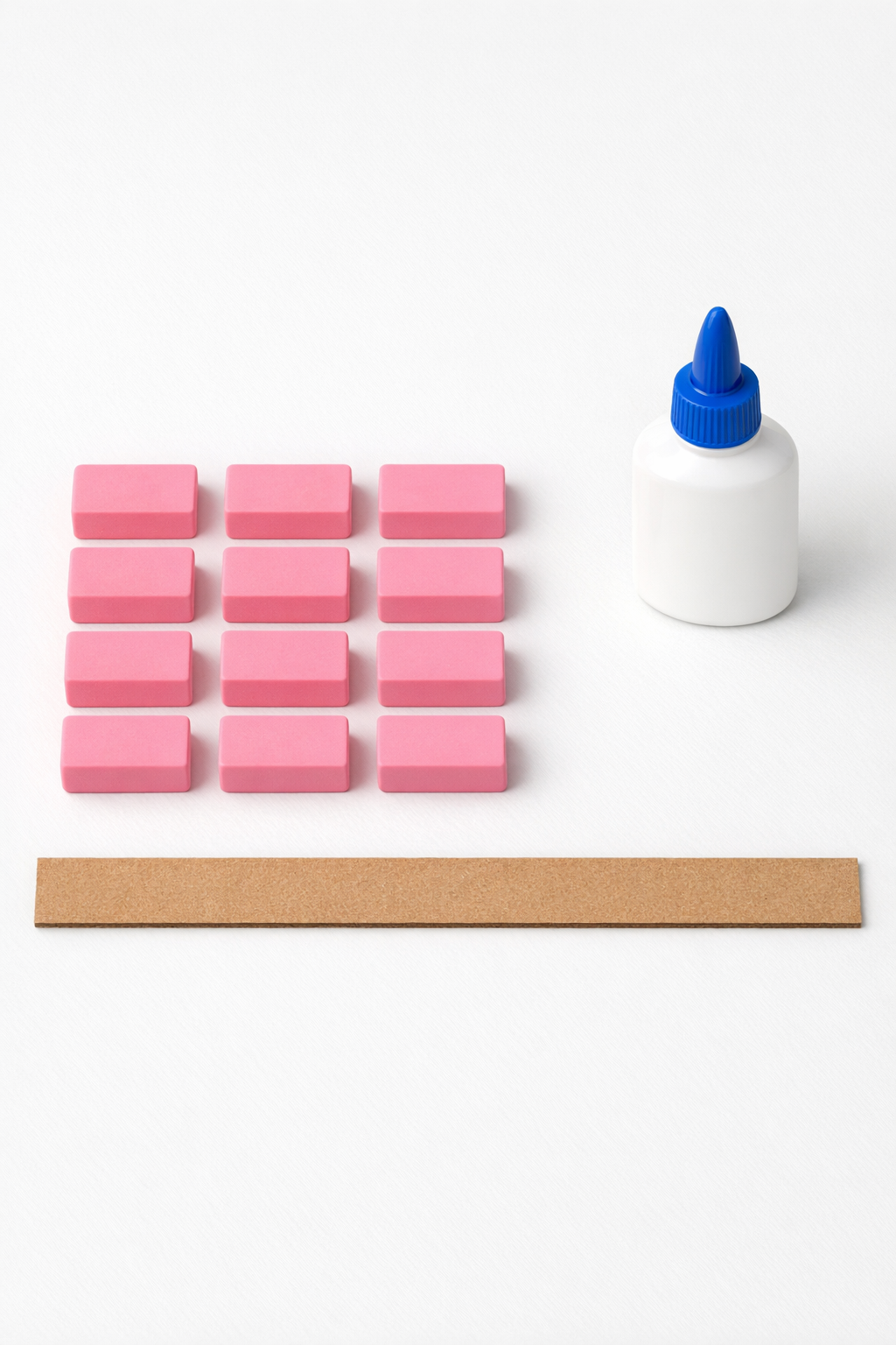 Pink school erasers, craft glue, and a cardboard strip laid out for the project