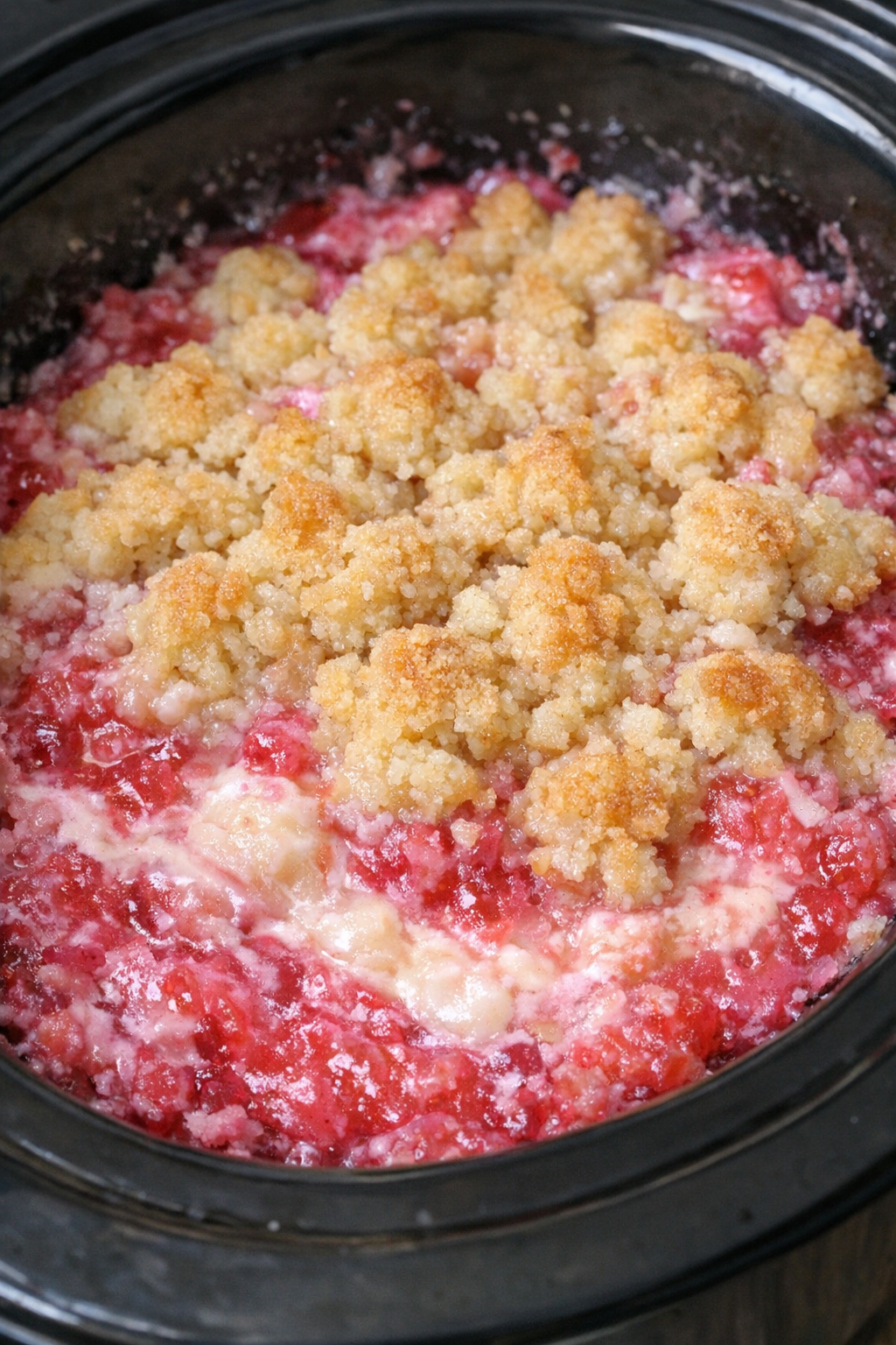 Slow cooker pink coconut refresher cobbler in a black slow cooker