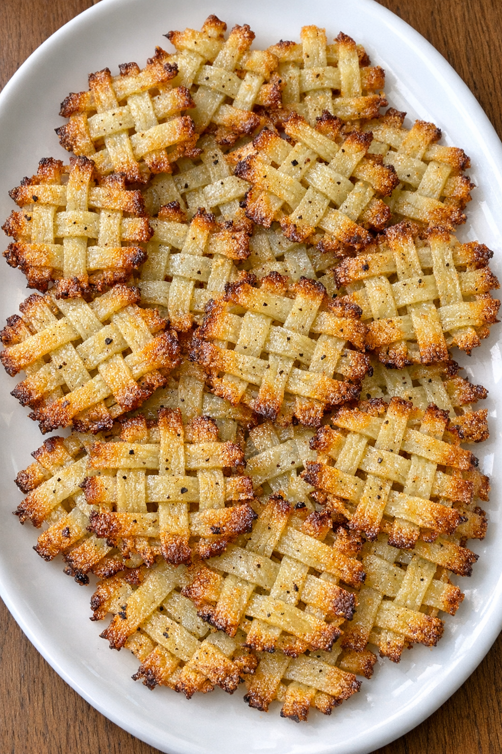 Golden crispy woven potato lattice bites on a white oval platter