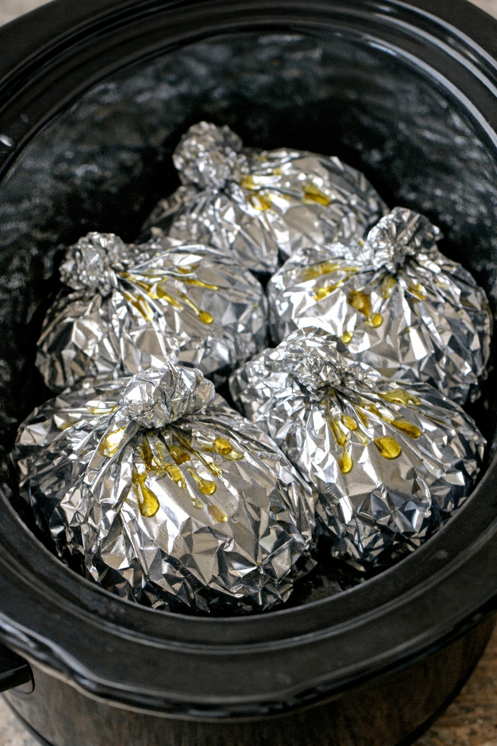 Slow cooker cheesy spinach ravioli foil packets in a black slow cooker