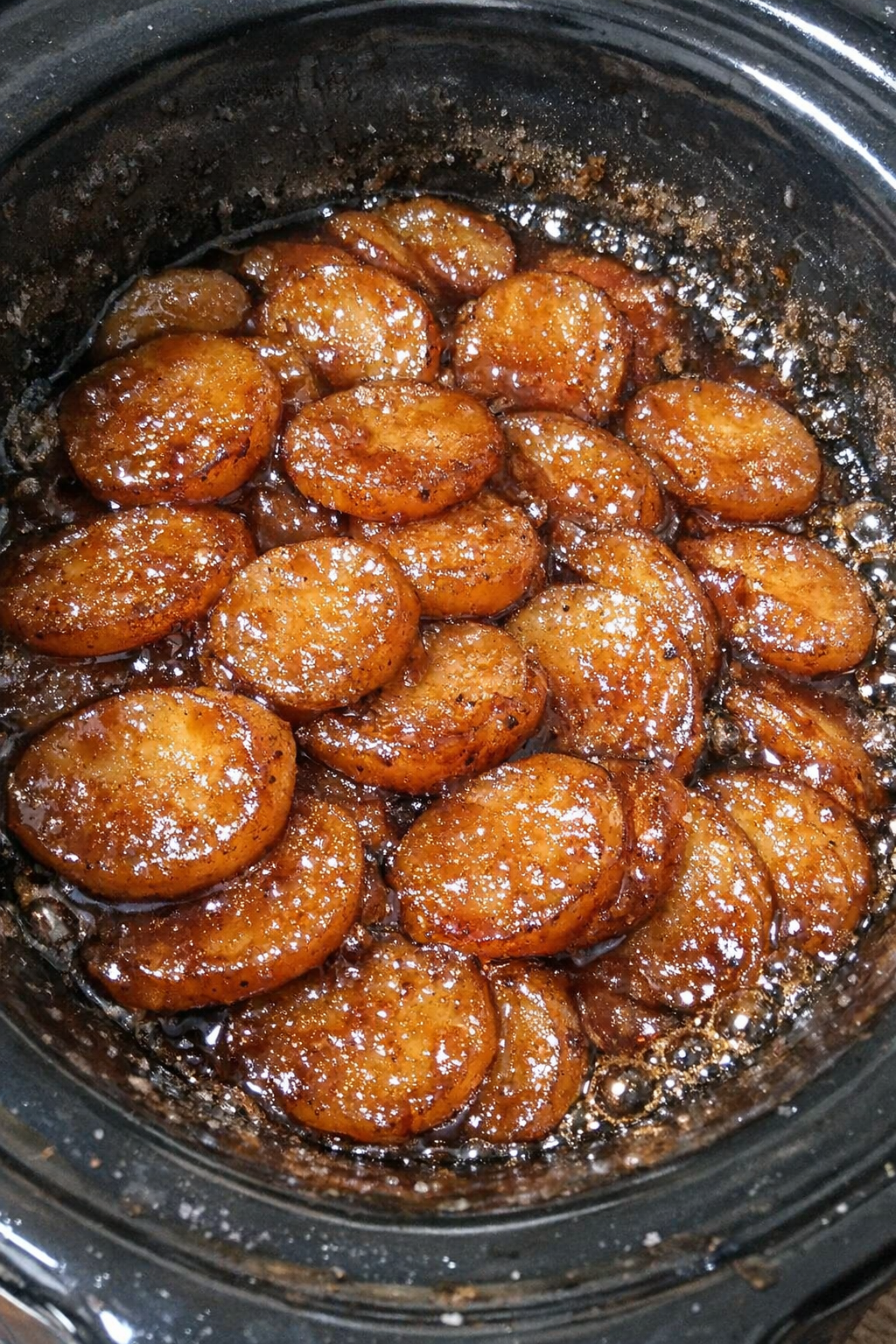 Glossy caramelized starchy coins in amber sauce bubbling in a slow cooker