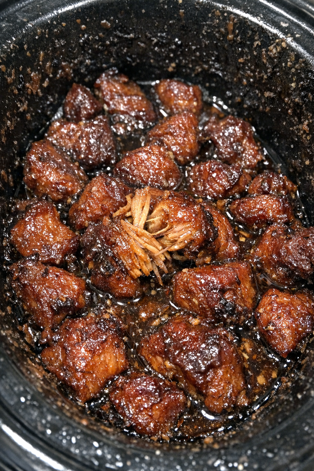 Gelatinous, caramelized protein chunks in a sticky amber sauce in a slow cooker
