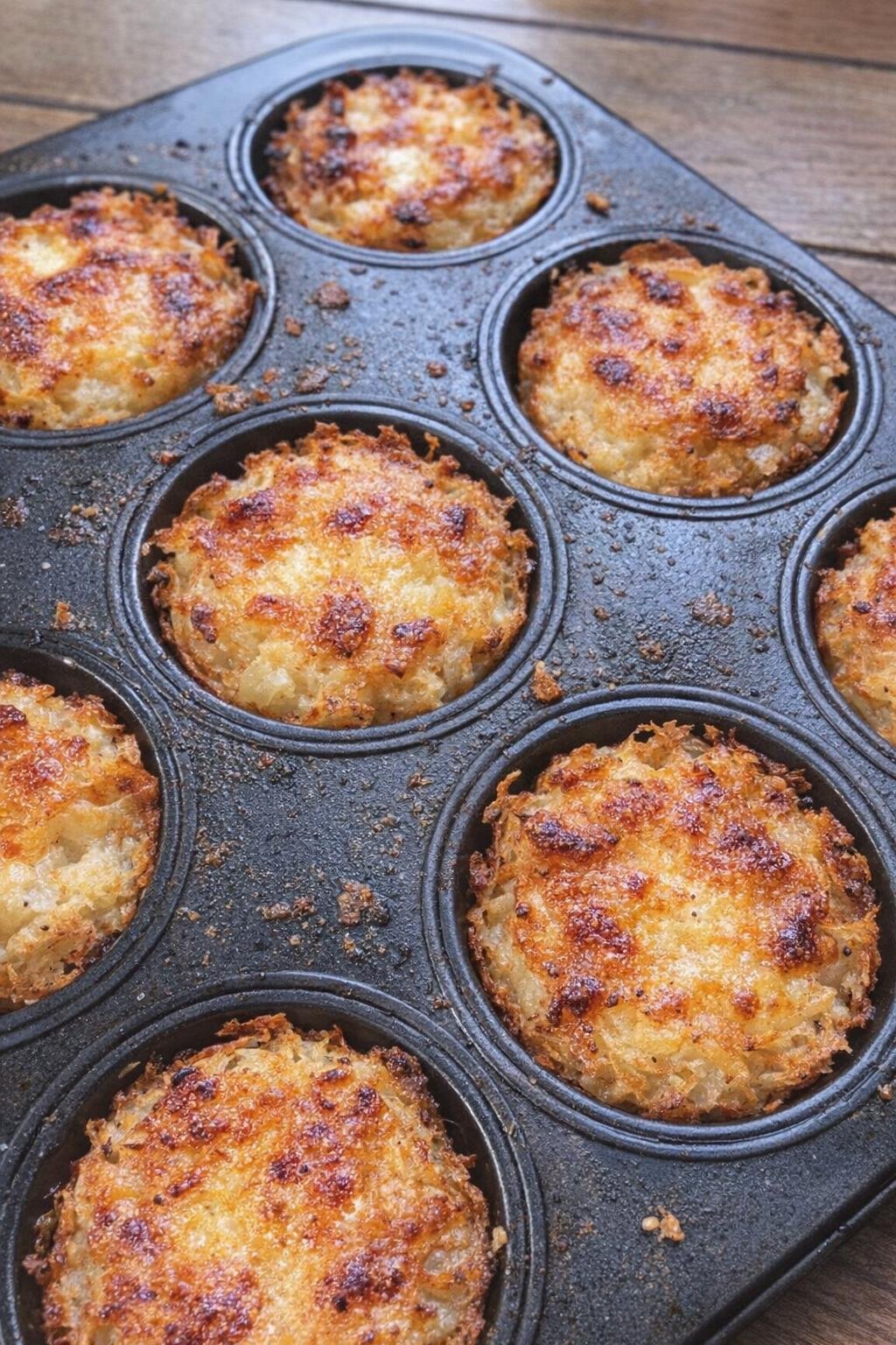 Golden crispy hash brown nests with melted cheese centers in a muffin tin