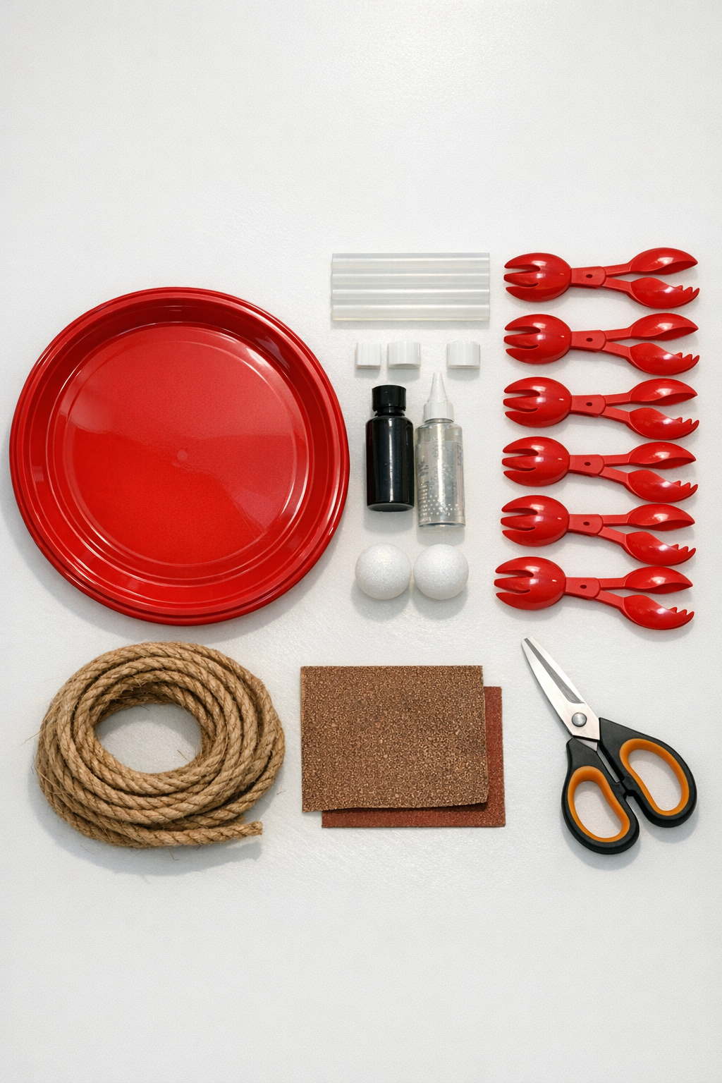Red plastic serving tray, red salad tongs, glue, hanging hardware, and paint supplies laid out for the project