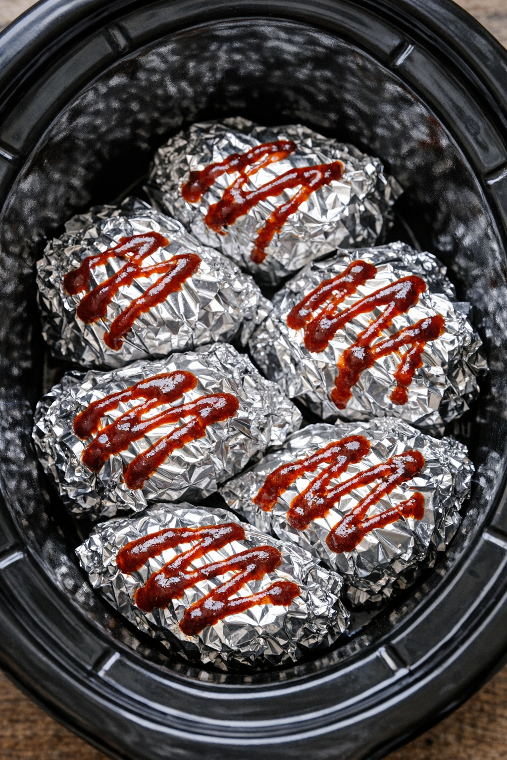 Slow cooker chipotle beef foil packets in a black slow cooker