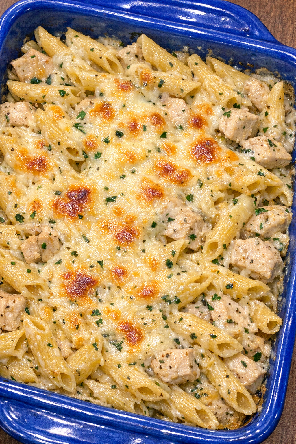 Golden chicken penne bake in a blue ceramic baking dish