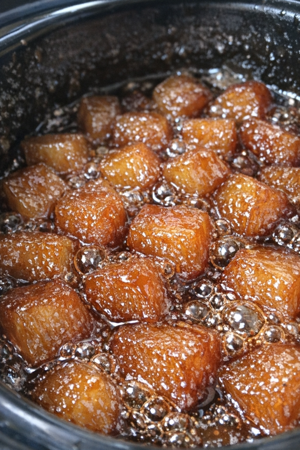 Gelatinous caramelized cubes in dark amber syrup inside a slow cooker