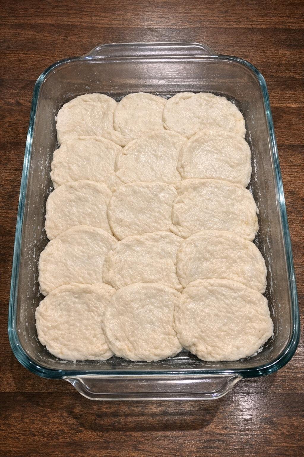 Flattened biscuit rounds pressed into the baking dish