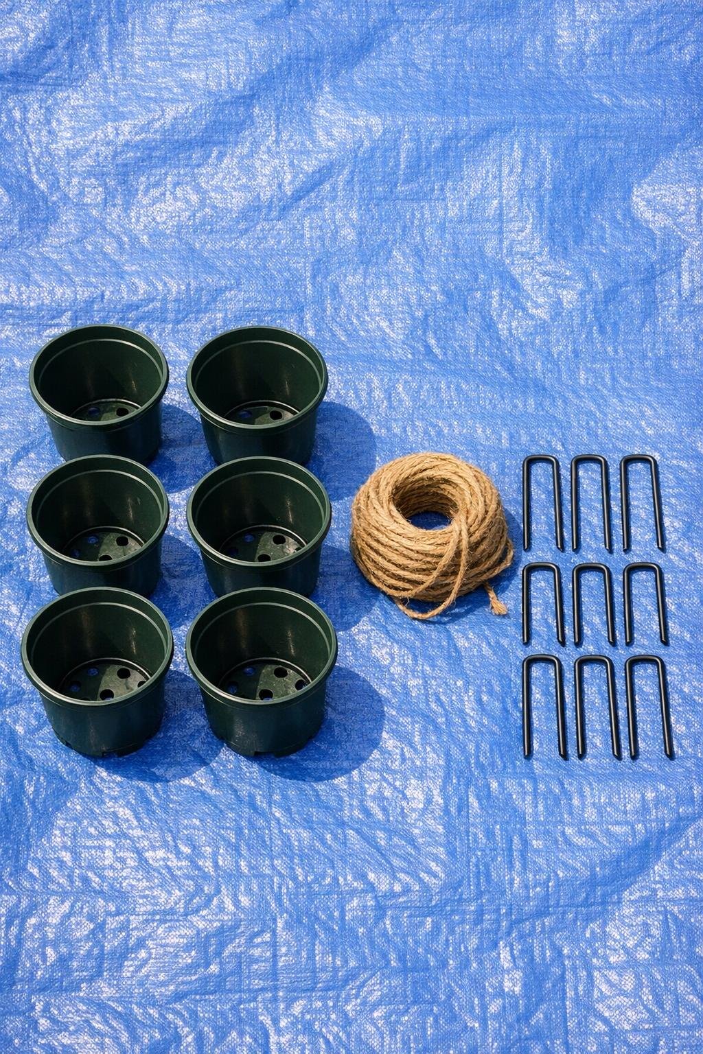 Plastic nursery pots, twine, and landscape pins laid out on a tarp