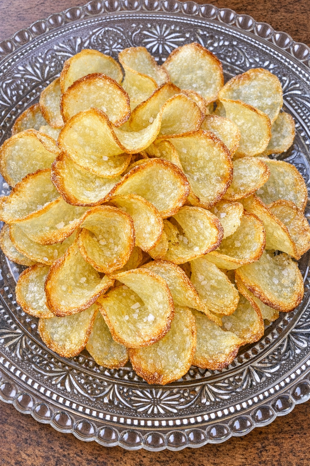 Paper-thin golden potato wafer curls on a vintage glass platter