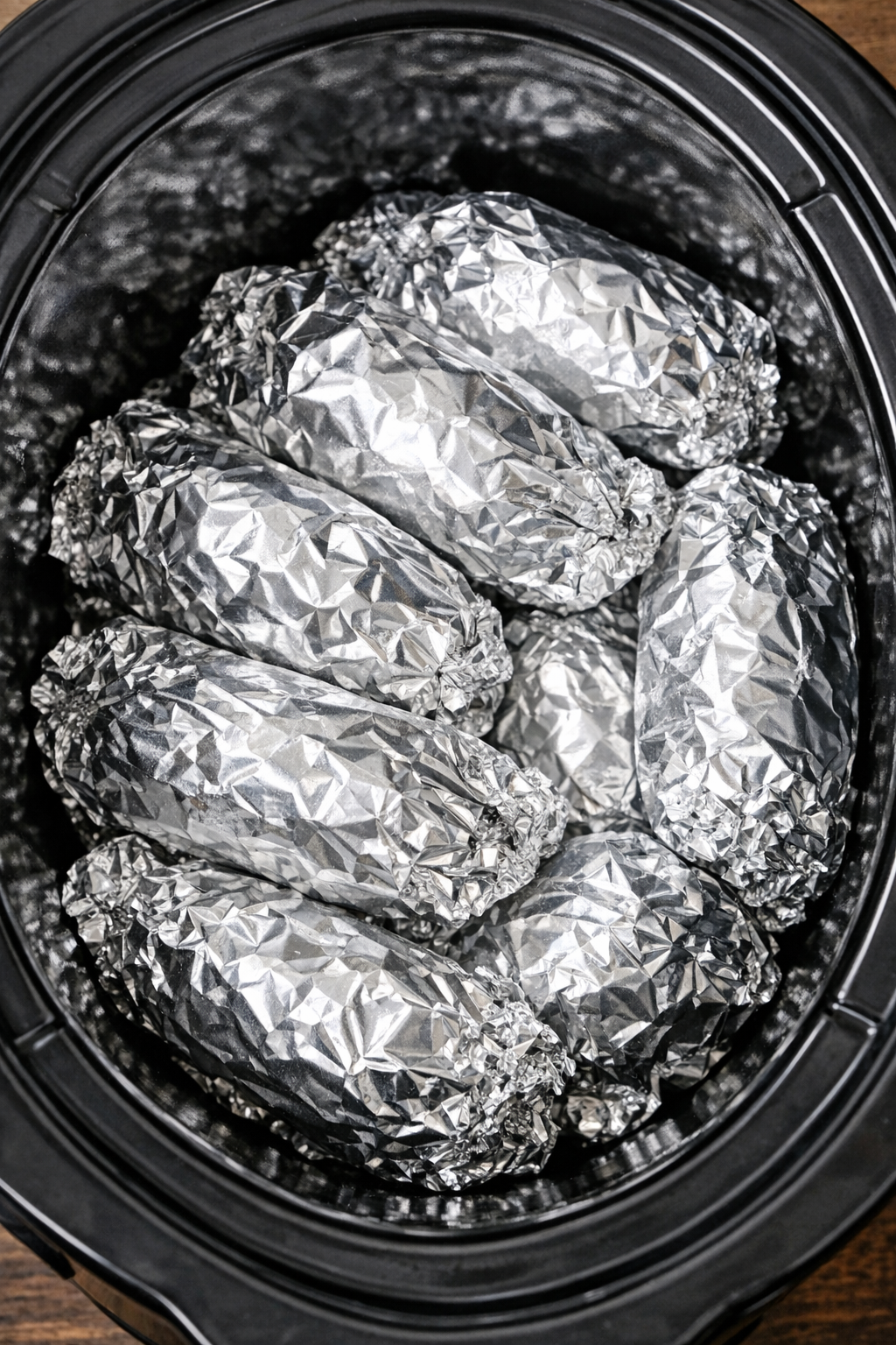 Slow cooker beef and poblano foil packets in a black slow cooker