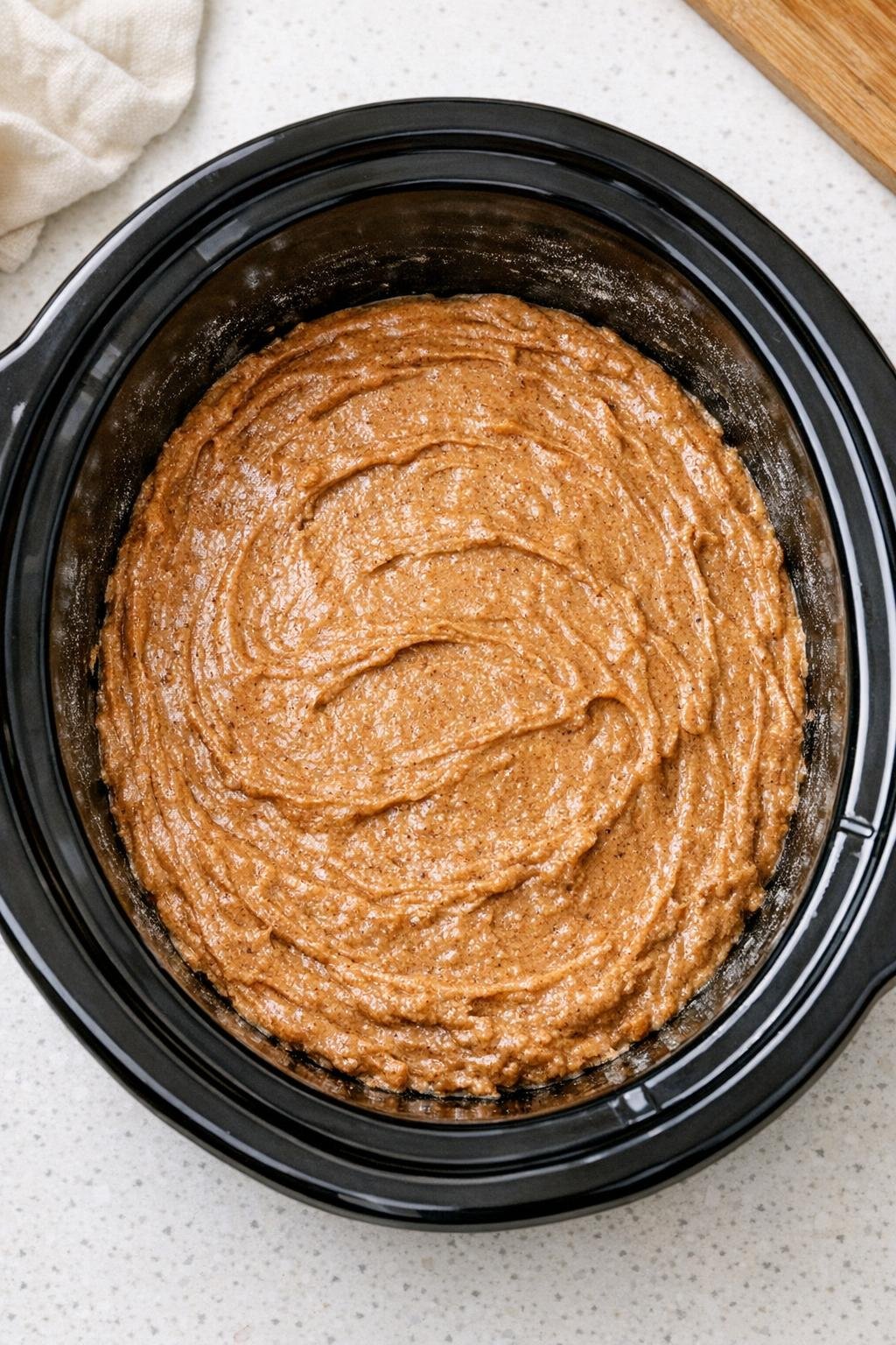 Kruidencakebeslag uitgespreid in een slowcooker