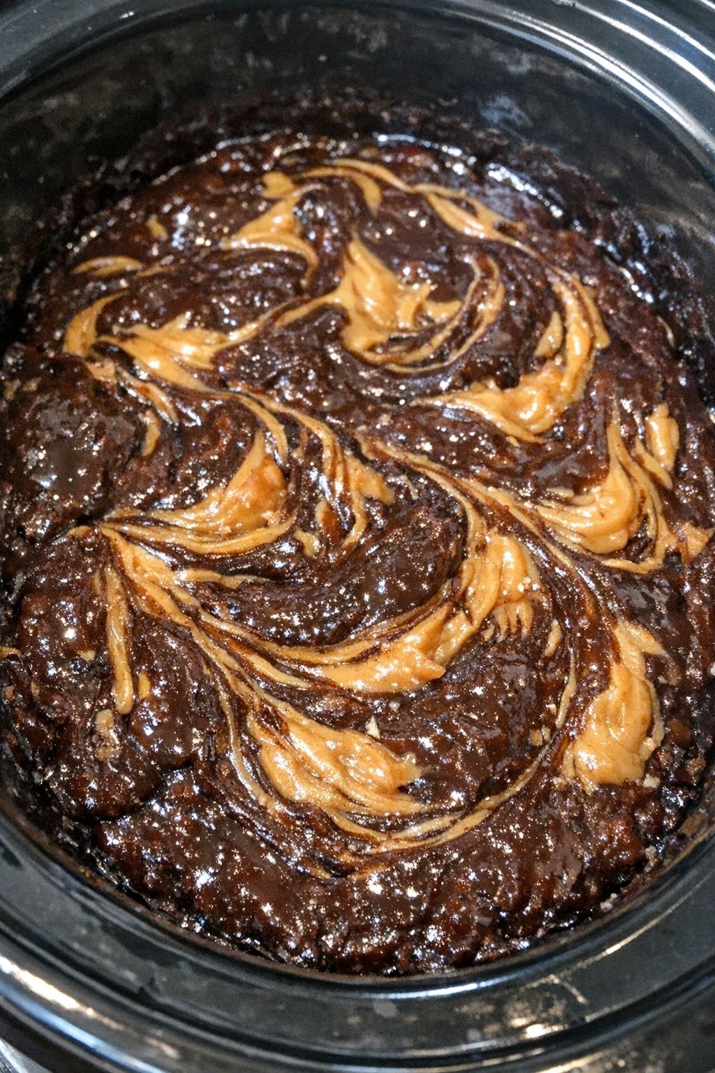 Dense mahogany mass in a slow cooker with peanut butter-colored swirls