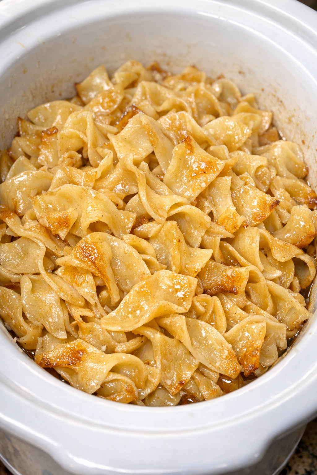Slow cooker Amish honey butter noodles in a white slow cooker