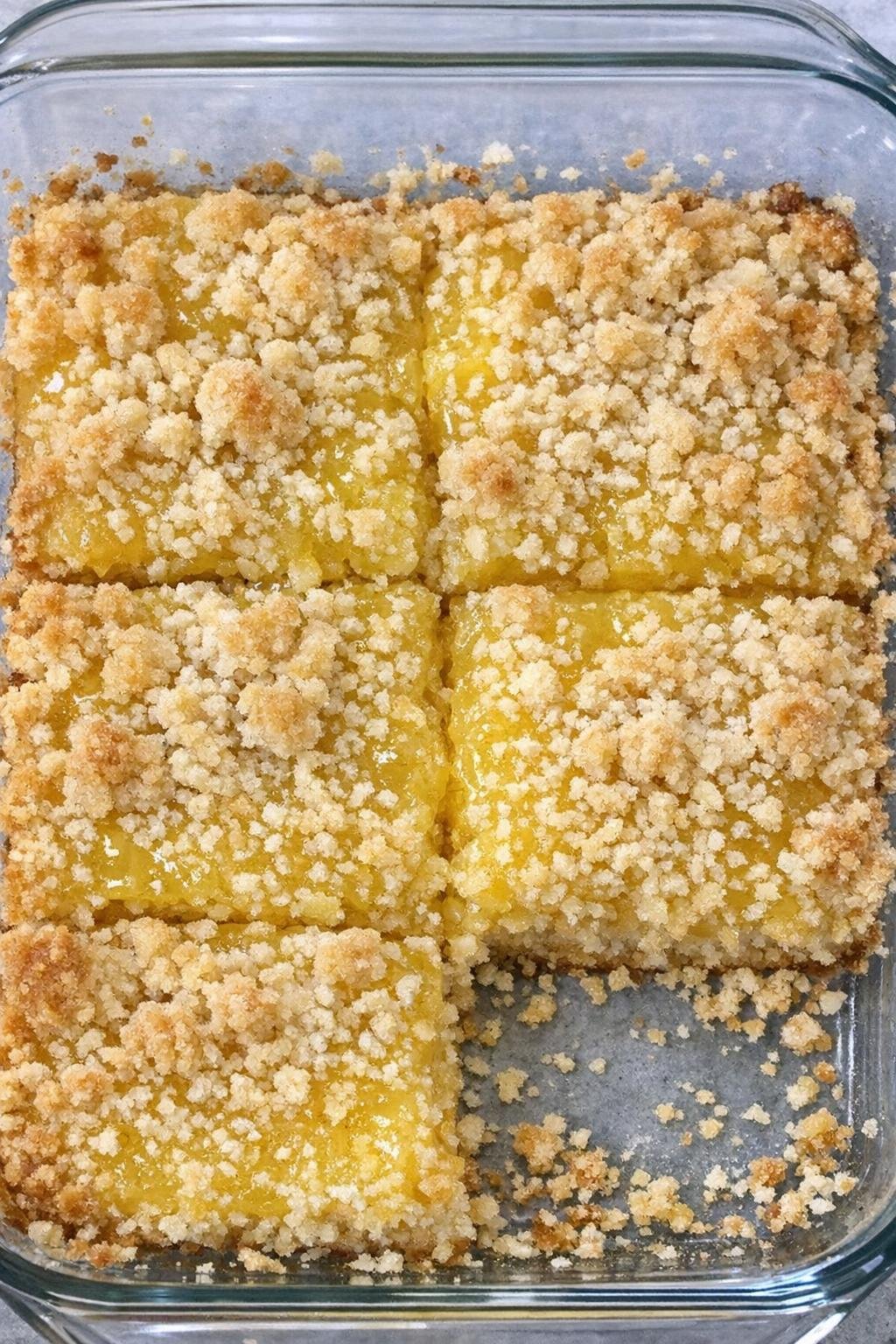 Lemon crumb bars cut into squares in a glass casserole dish