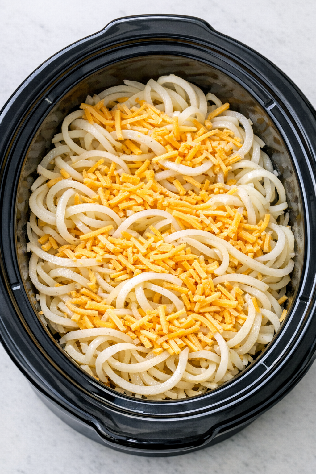 Layering potato spirals and cheddar in slow cooker